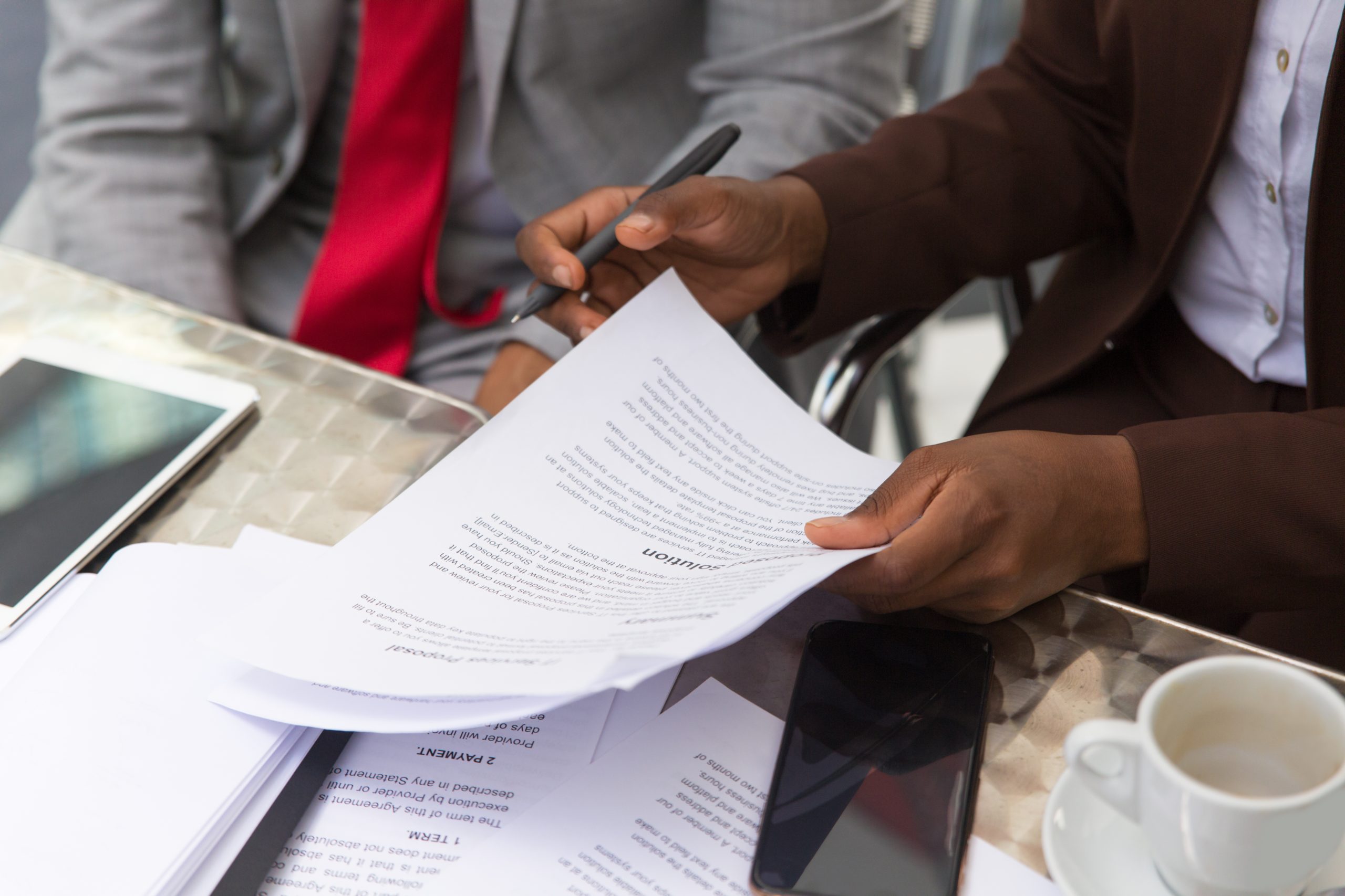 Businessman consulting legal expert in coffee shop. Closeup of business man and woman sitting in cafe and reading documents. Paperwork concept